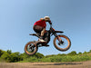 A rider doing a jump on an Isinwheel Monster Pro Mid-Drive Electric Dirt Bike