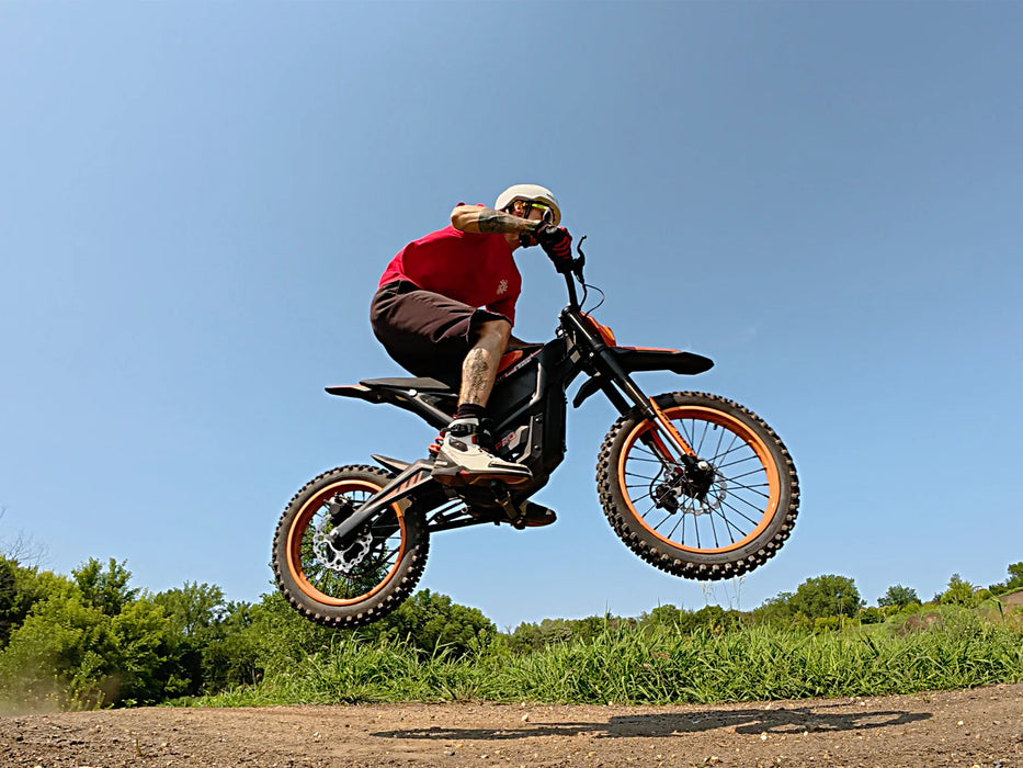 A rider doing a jump on an Isinwheel Monster Pro Mid-Drive Electric Dirt Bike